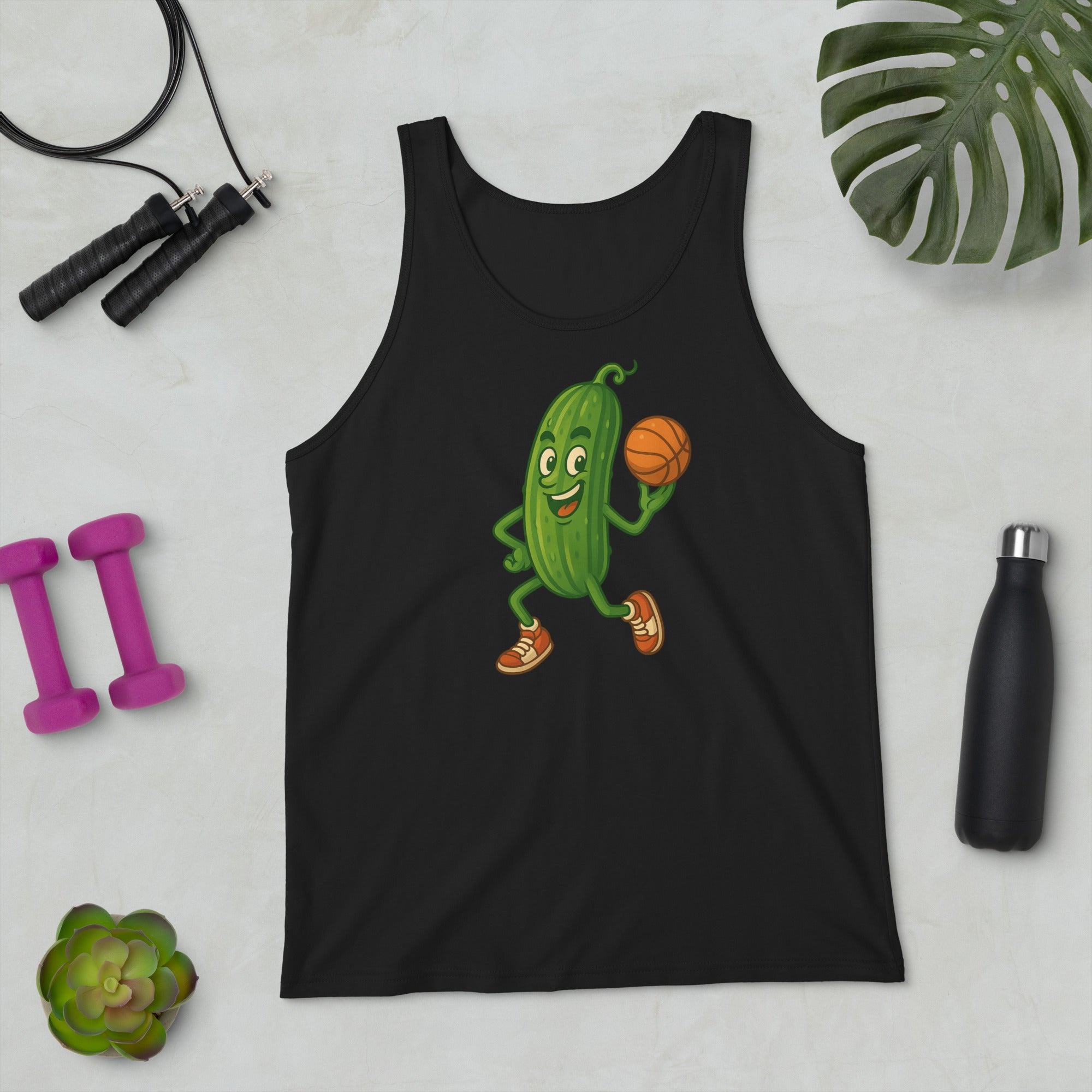Black tank top with a cartoon pickle playing basketball design, surrounded by fitness items on a light surface.