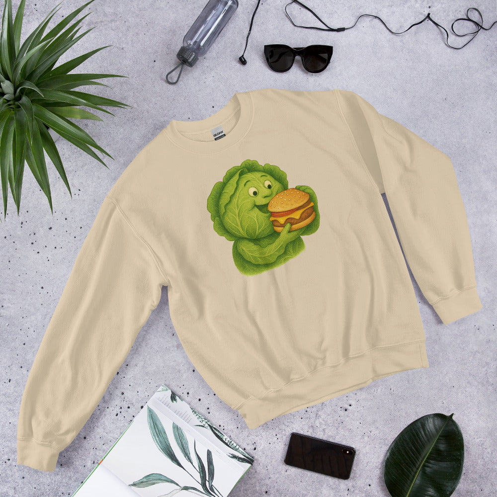 Beige sweatshirt with a green character holding a burger on a gray surface with plants and accessories.