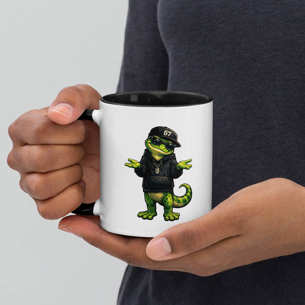 Person holding a mug with a gekko wearing sunglasses and a jacket 67 design.