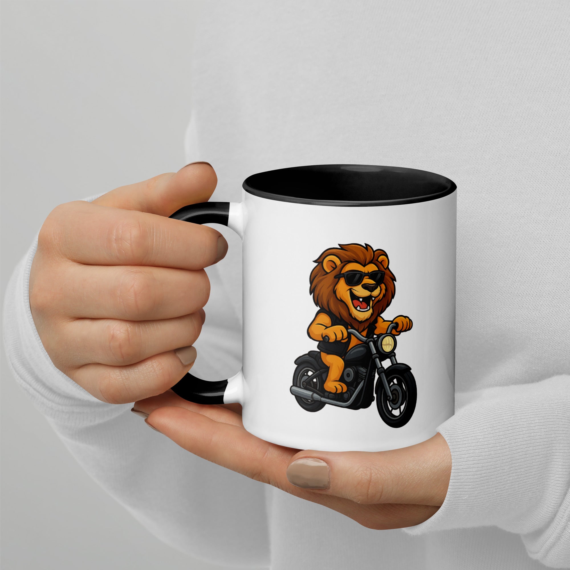 White mug with a lion on a motorcycle design, held by a person against a light gray background