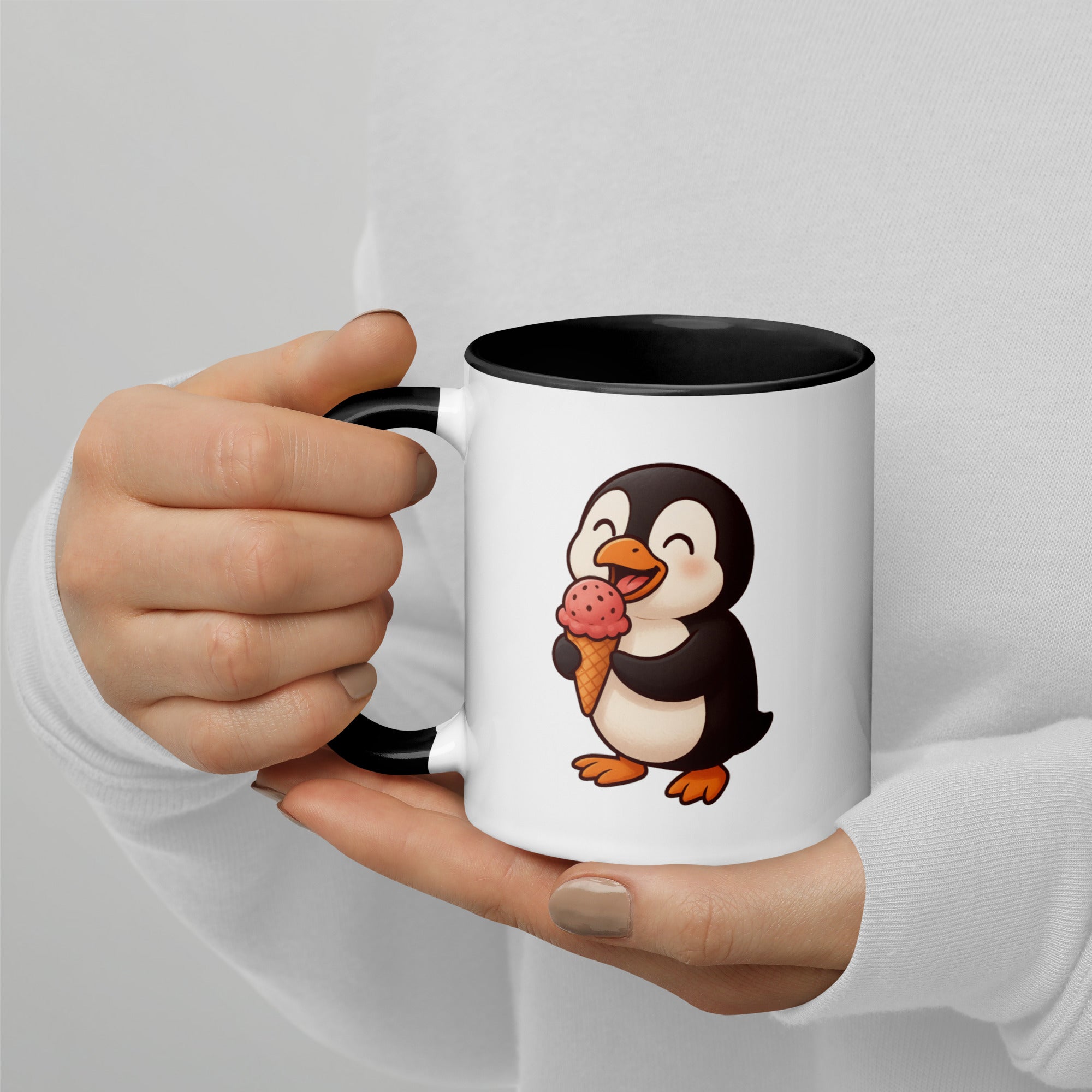 Mug with a penguin design holding ice cream, held by a person against a light gray background