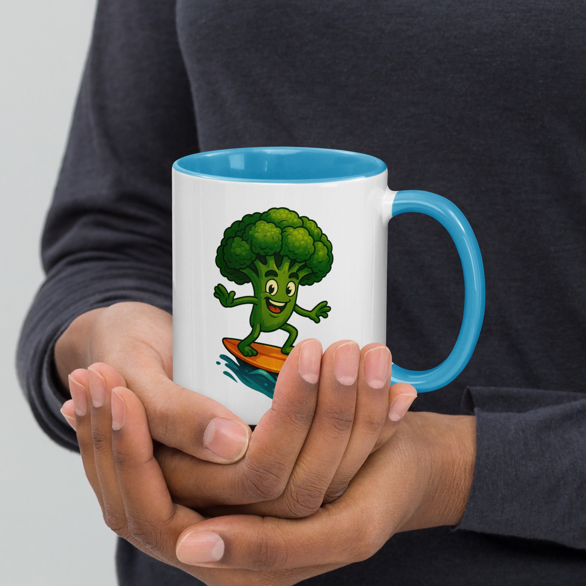 Colorful ceramic mug with a cartoon broccoli character surfing, held in hands.