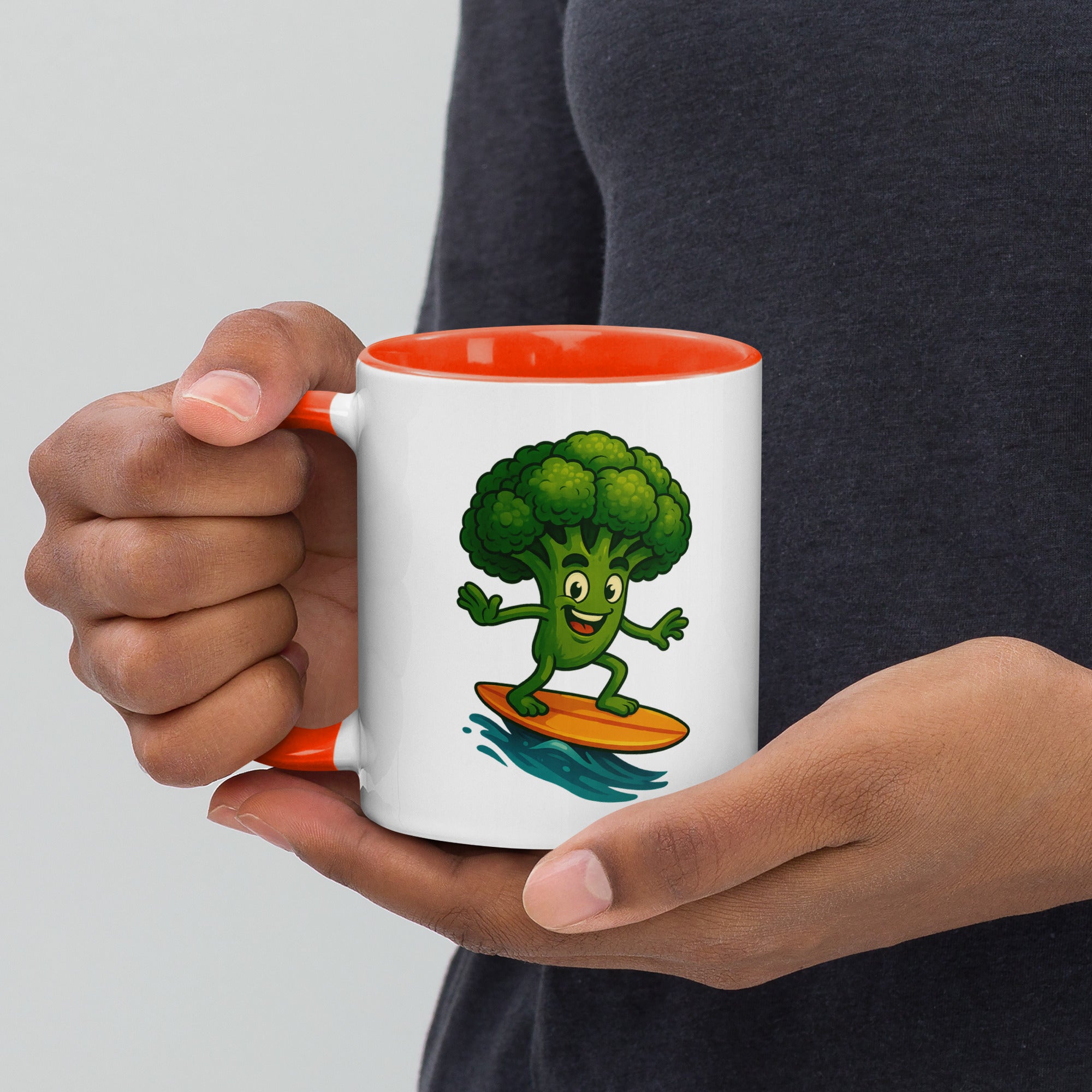 Colorful ceramic mug featuring a cartoon broccoli character surfing on a wave, with an orange interior.