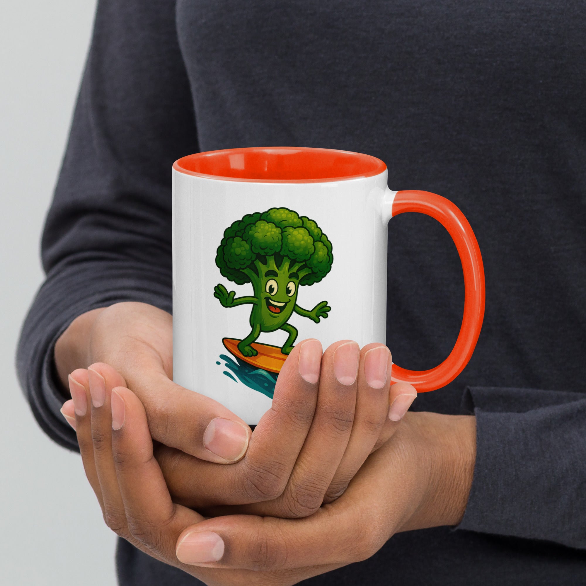 Colorful ceramic mug with a cartoon broccoli character surfing, featuring an orange handle and interior.