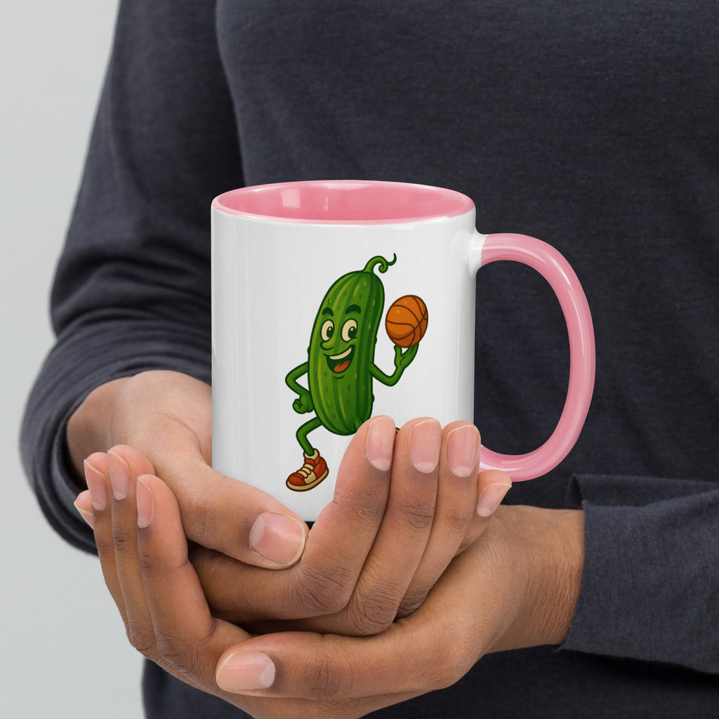 Colorful ceramic mug with a playful pickle character holding a basketball, featuring a pink interior.