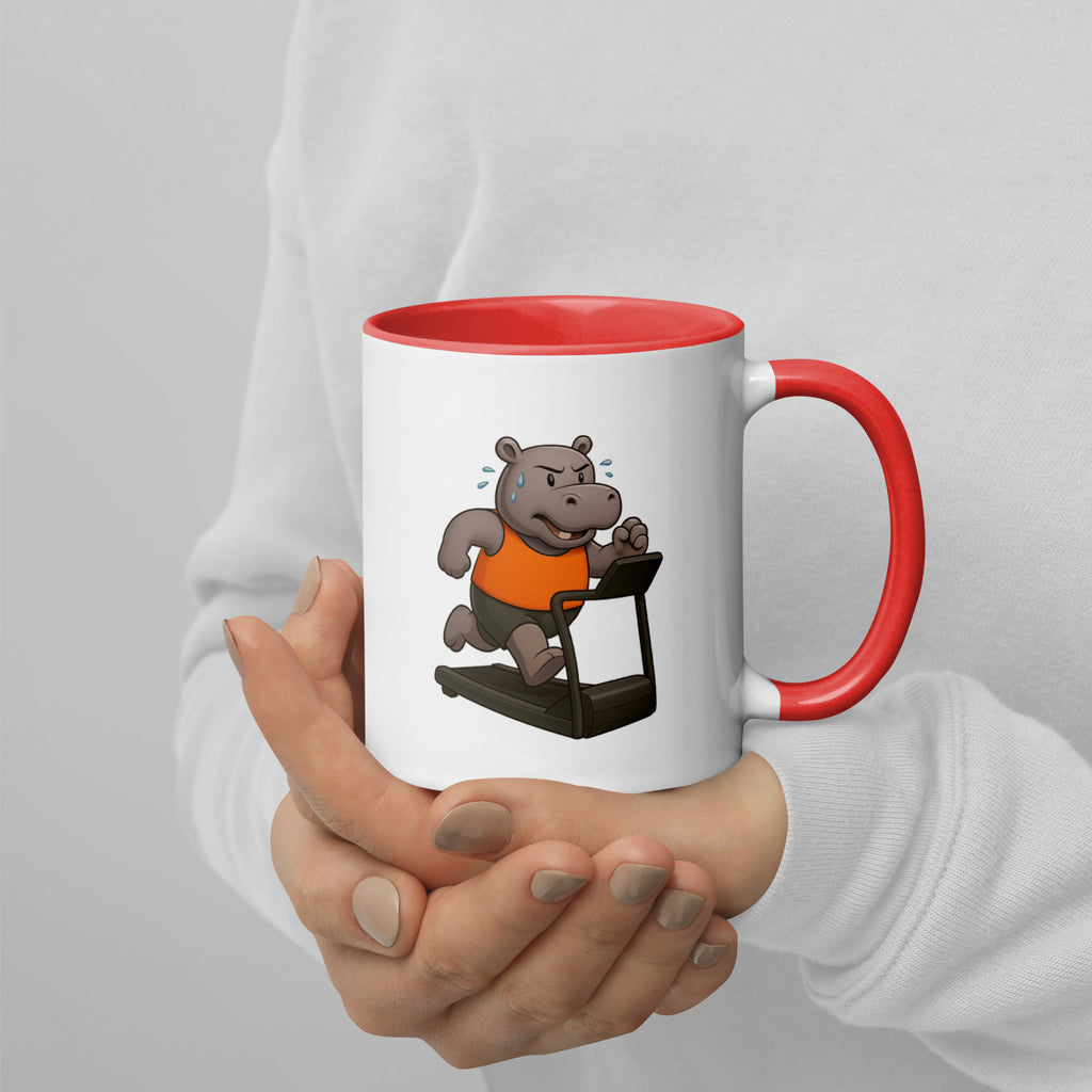 Mug with a cartoon hippo on a treadmill design, held by a person against a light gray background
