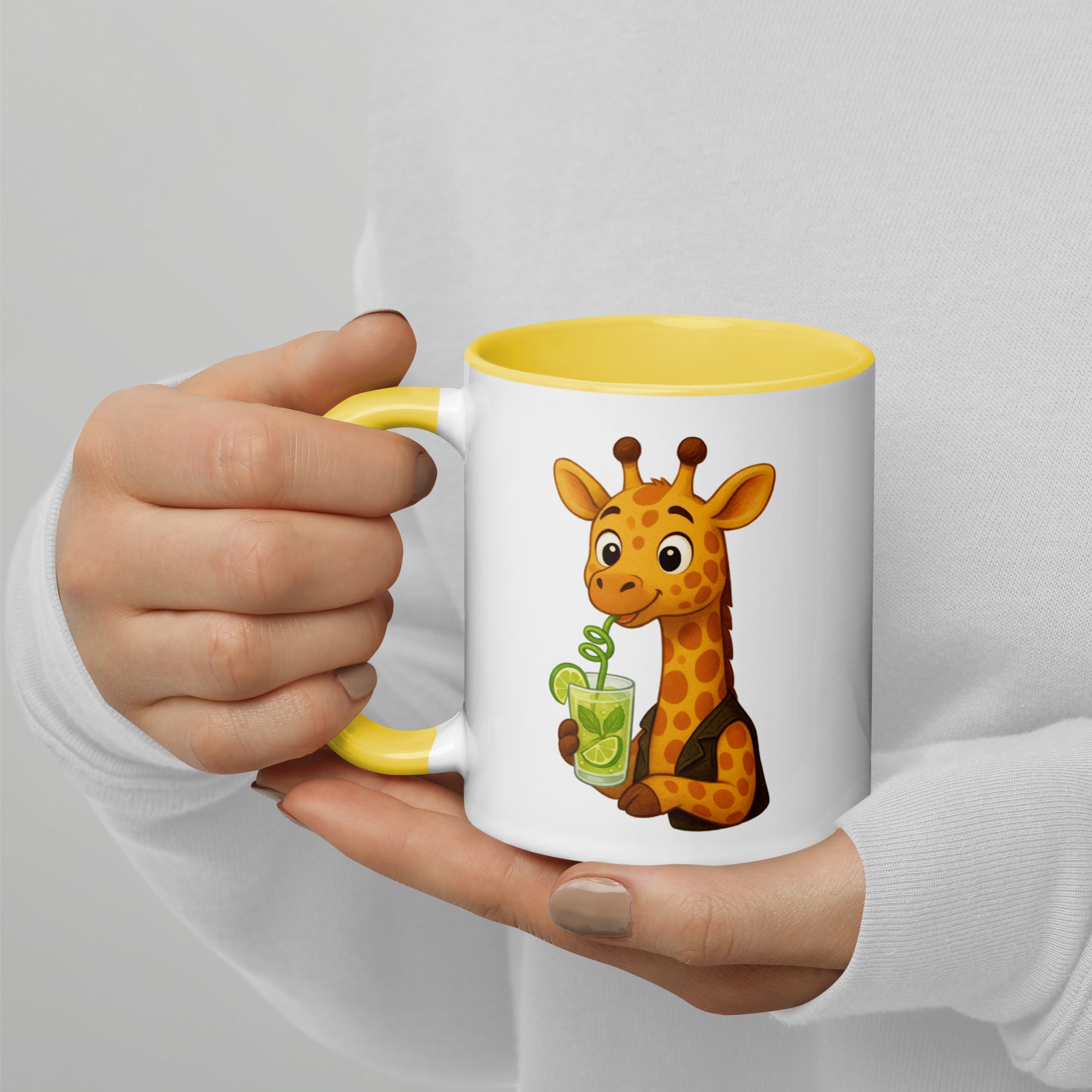 White mug with yellow interior and handle, featuring a cartoon giraffe holding a drink, held by a person.