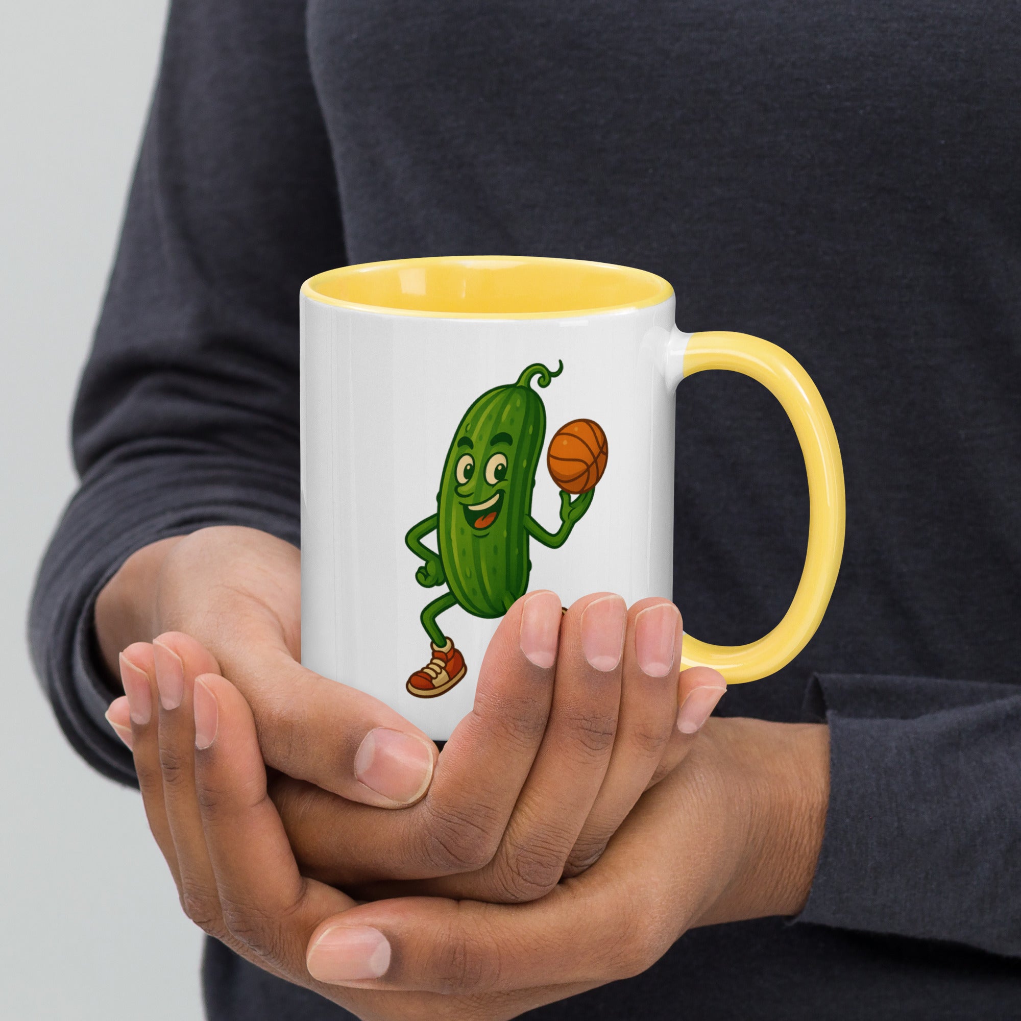 Whimsical pickle character holding a basketball on a mug with a yellow interior.