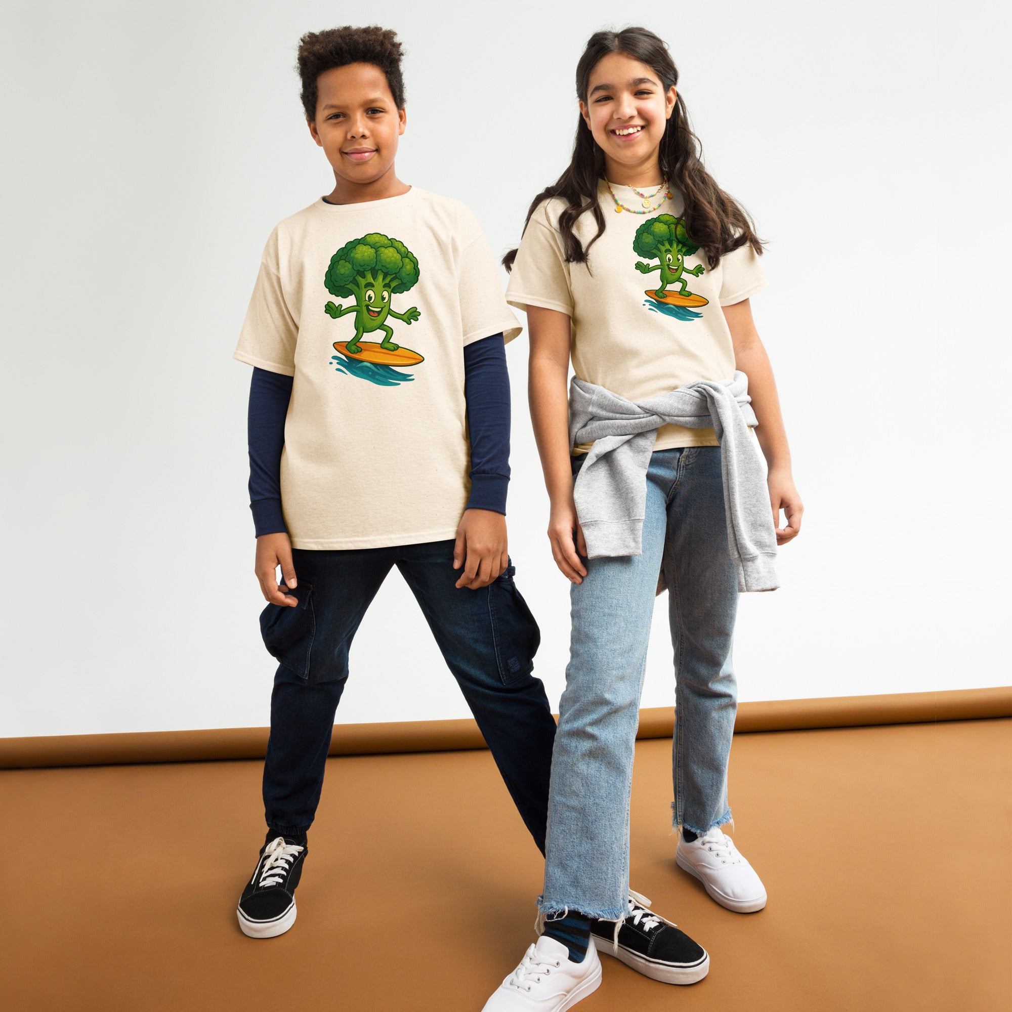 Two children wearing t-shirts with broccoli graphics on a plain background