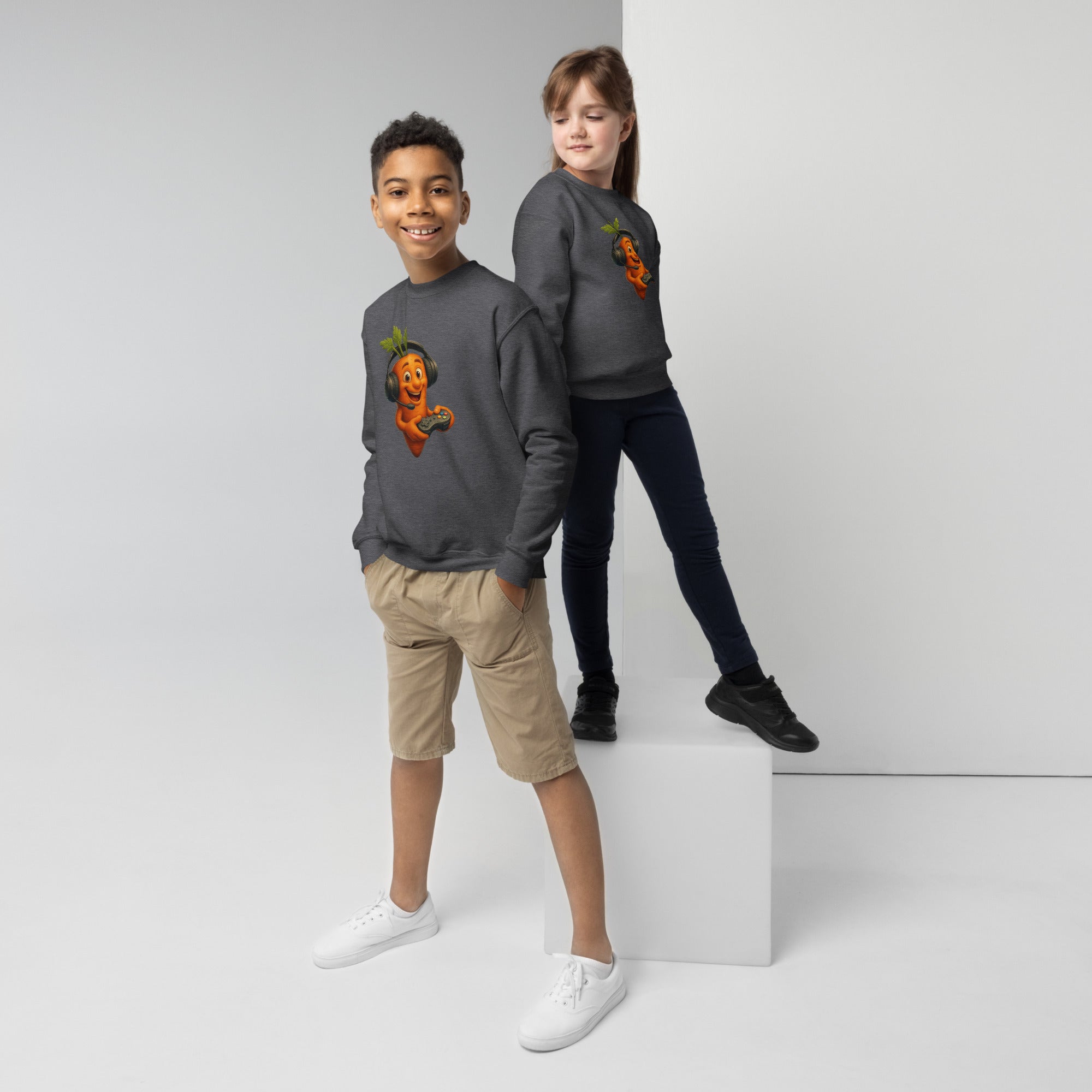 Two kids modeling youth crewneck sweatshirts; one in gray with fun carrot design, showcasing a casual, stylish look.